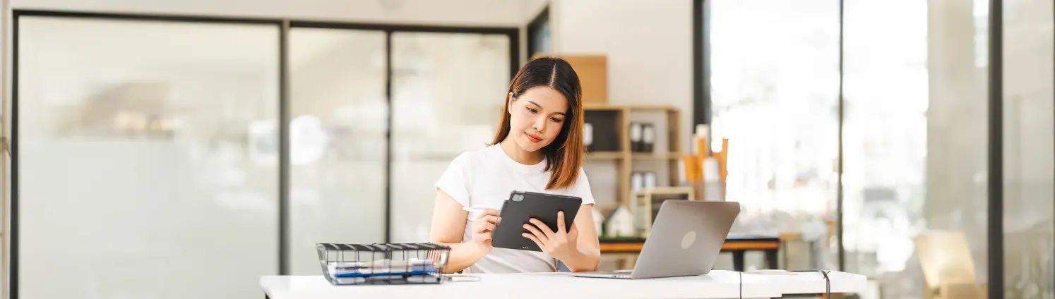 Eine Frau sitzt an ihre am Laptop und Tablet