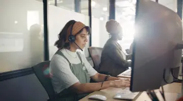 Eine Frau sitzt im Kundenservice an einem Laptop